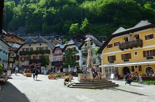 Ein sonniger Dorfplatz in Hallstatt mit einem Brunnen und typisch österreichischen Häusern