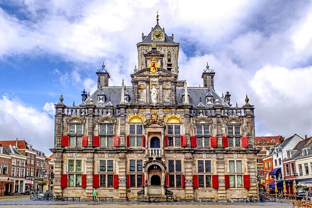 Rathaus im niederländischen Delft mit roten Fensterläden und goldfarbenen Elementen